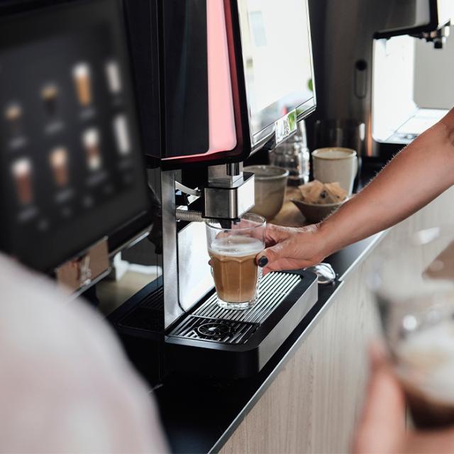 kvinde laver kaffe fra fuldautomatisk kaffemaskine som giver god smagsoplevelse
